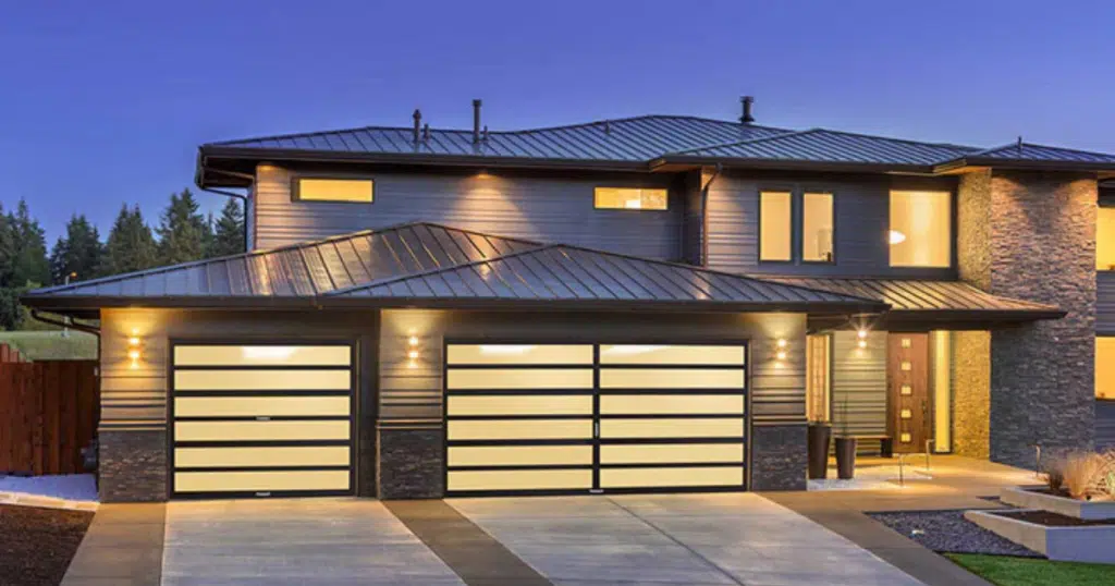 Modern home with glass garage doors lit.