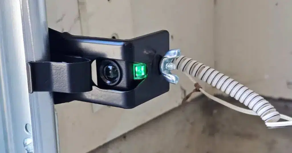 Garage door sensor with glowing green light.