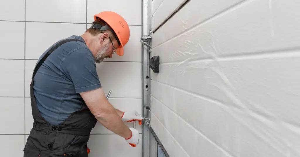 Man fixing garage door with a wrench.